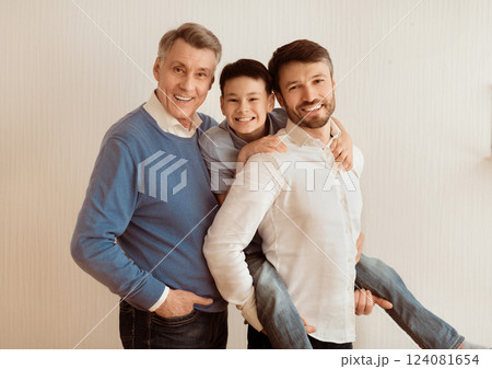 Mature Man With Son And Senior Father Posing Smiling At Camera Standing Near White Wall Indoor. Male Generations Friendship Mature Man With Son And Senior Father Posing Smiling At Camera Standing Near White Wall Indoor. Male Generations Friendship 124081654