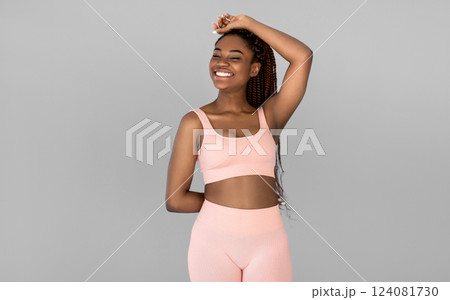 Portrait of happy young black woman in sports outfit posing and smiling on grey studio background. Fit millennial African American female being in great shape, leading active lifestyle Portrait of happy young black woman in sports outfit posing and smiling on grey studio background. Fit millennial African American female being in great shape, leading active lifestyle 124081730