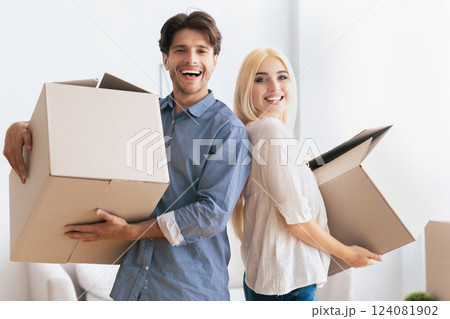 A happy couple smiles while carrying boxes in their new home. A happy couple smiles while carrying boxes in their new home. 124081902