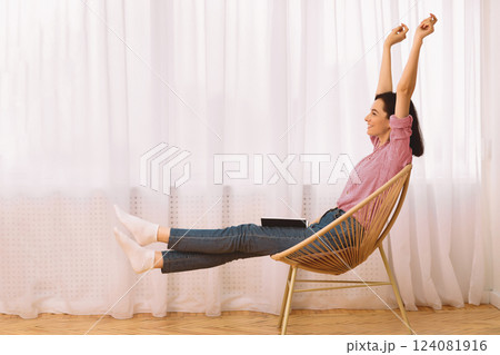 Weekends Finally. Young woman raising hands sitting in modern chair with a book on her lap, stretching body, copyspace Weekends Finally. Young woman raising hands sitting in modern chair with a book on her lap, stretching body, copyspace 124081916