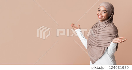 I don't care. Carefree afro islamic girl in headscarf spreading hands and shrugging shoulders, posing over yellow background with free space 124081989