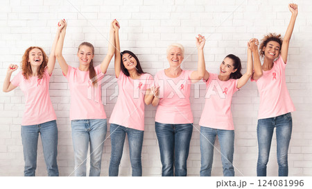 Breast Cancer Support Group. Women In Pink T-Shirts With Ribbons Holding Raised Hands Celebrating Successful Treatment Over White Wall. Panorama Breast Cancer Support Group. Women In Pink T-Shirts With Ribbons Holding Raised Hands Celebrating Successful Treatment Over White Wall. Panorama 124081996