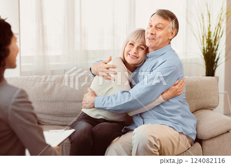 Psychotherapy. Happy senior couple sitting on couch and hugging, smiling female doctor listening, copyspace Psychotherapy. Happy senior couple sitting on couch and hugging, smiling female doctor listening, copyspace 124082116