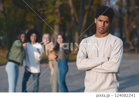Upset african guy standing over laughing group of international teenagers, bullying concept 124082241