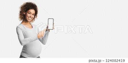 African-american pregnant woman showing cellphone with empty display, application for expectant ladie 124082419
