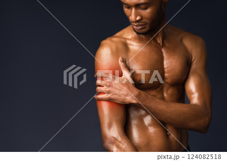 Pain In The Shoulder. Muscular black bodybuilder touching hand with red sore zone, sports injury, copyspace Pain In The Shoulder. Muscular black bodybuilder touching hand with red sore zone, sports injury, copyspace 124082518