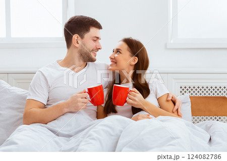 Good Morning. Happy Couple Having Coffee Hugging Lying In Bed At Home. 124082786