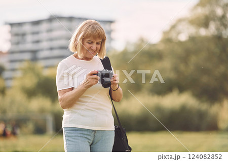 Photographer with a camera. Senior woman having nice weekend outdoors on the field at sunny day 124082852
