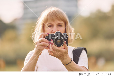 Using the camera. Making the photos. Senior woman having nice weekend outdoors on the field at sunny day Using the camera. Making the photos. Senior woman having nice weekend outdoors on the field at sunny day 124082853