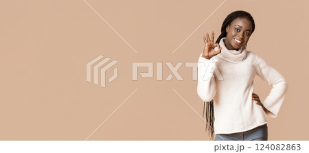 Happy black winter lady showing okay sign over beige studio background, free space, panorama 124082863