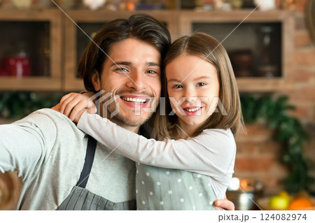 Selfie Fun. Cheerful Little Girl Taking Self-Portrait With Dad In Kitchen, Cuddling Father And Posing At Camera While Cooking Dinner Together, Closeup 124082974