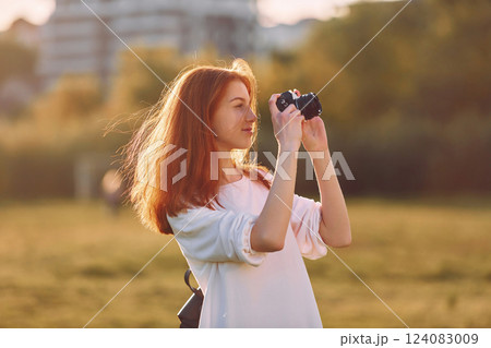 Photographer is with camera. Young girl is on the field at sunny daytime having nice weekend Photographer is with camera. Young girl is on the field at sunny daytime having nice weekend 124083009