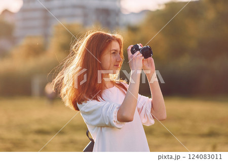 Photographer is with camera. Young girl is on the field at sunny daytime having nice weekend Photographer is with camera. Young girl is on the field at sunny daytime having nice weekend 124083011