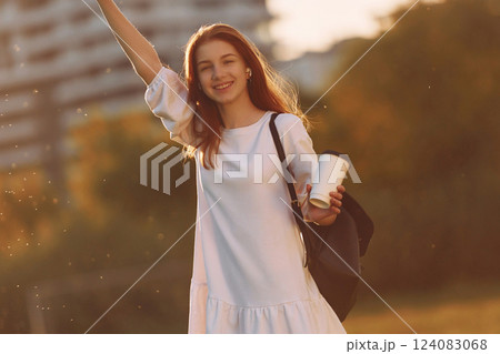 Greetings gesture. Young girl is on the field at sunny daytime having nice weekend 124083068
