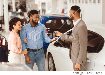 Buying Auto. Salesman Giving Car Key To Buyers For Test Drive Standing In Luxury Dealership Center. 124083244