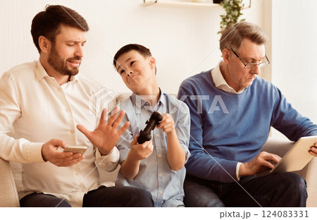 Indifference. Busy Father And Grandfather Refusing To Play Video Game With Boy Siitting On Sofa Indoor. Selective Focus Indifference. Busy Father And Grandfather Refusing To Play Video Game With Boy Siitting On Sofa Indoor. Selective Focus 124083331