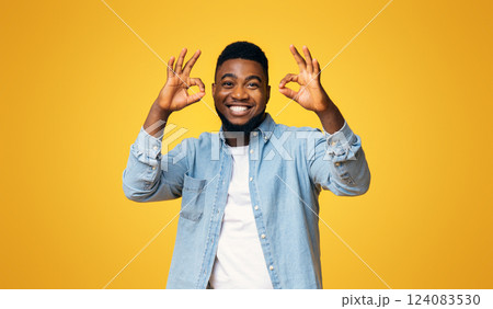 Everything is OK. Joyful african american man showing okay gesture with two hands over yellow studio background, free space 124083530