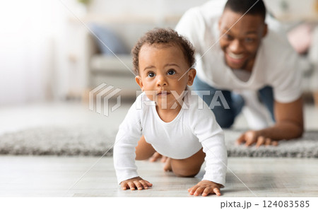 Happy Black Father Looking At Adorable Infant Baby Crawling On Floor At Home, Proud African American Dad Spending Time With His Cute Toddler Child, Enjoying Paternity Leave, Selective Focus Happy Black Father Looking At Adorable Infant Baby Crawling On Floor At Home, Proud African American Dad Spending Time With His Cute Toddler Child, Enjoying Paternity Leave, Selective Focus 124083585