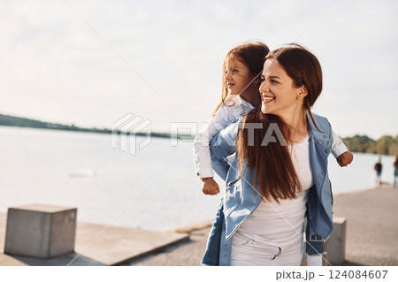 Positive emotions. Young mother with her daughter having fun outdoors near the lake at summer 124084607