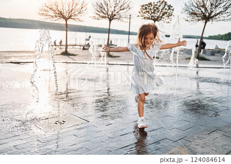 Happy little girl having fun outdoors in the fountain near the lake at summer Happy little girl having fun outdoors in the fountain near the lake at summer 124084614