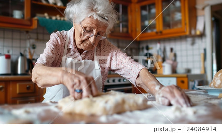 A senior woman happily rolls out dough in her kitchen, financial security from her state pension evident. 124084914