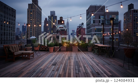 A city rooftop terrace features stylish wooden flooring and stunning skyline views, enhanced by string lights. 124084931