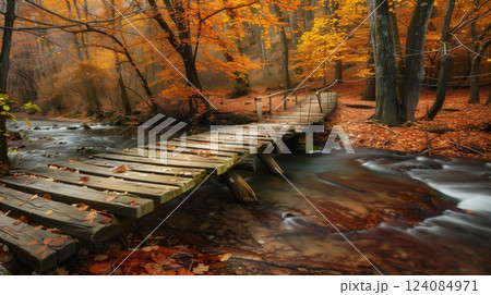 A wooden bridge spans a tranquil stream with impeccably aligned planks, amidst vibrant autumn foliage. 124084971