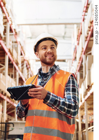 With tablet. Employee in uniform is working in the storage at daytime With tablet. Employee in uniform is working in the storage at daytime 124085044