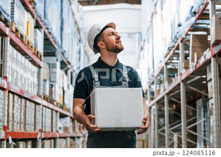 With delivery package in hands. Employee in uniform is working in the storage at daytime With delivery package in hands. Employee in uniform is working in the storage at daytime 124085116