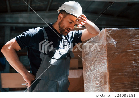 Tired employee in uniform is working in the dark storage 124085181