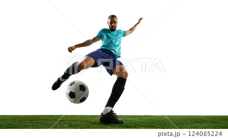 Forward view football player striking ball with full power, showing intensity in expression, precise control on grassy playground. Forward view football player striking ball with full power, showing intensity in expression, precise control on grassy playground. 124085224