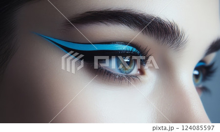 A close-up view showcases a striking makeup look with bold blue eyeliner applied expertly on a model's eye, highlighting the sharp lines and vibrant colors that enhance her natural beauty. 124085597