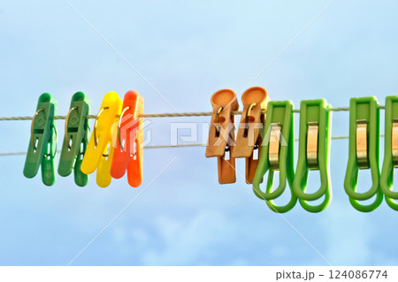 colored laundry clothespins of plastic, with metal clamping as spring). hanging on clothesline twine on open air (against overcast sky) colored laundry clothespins of plastic, with metal clamping as spring). hanging on clothesline twine on open air (against overcast sky) 124086774