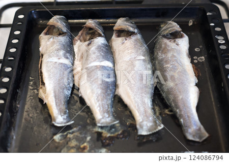 chilean sea bass cooked in the oven. fried on baking sheet four medium-sized bluish-gray fish. Exquisite dish of delicious rare fish 124086794