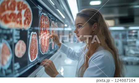 A medical expert studies detailed brain imaging data on a digital display, reflecting intense concentration in a modern lab environment. 124087104