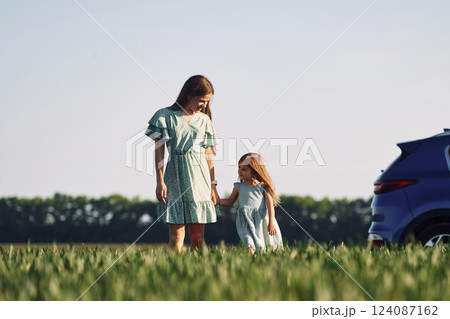 Holding each other by hands. Mother and daughter have fun outdoors on the field at summer Holding each other by hands. Mother and daughter have fun outdoors on the field at summer 124087162