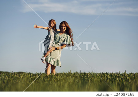 Holding girl on hands. Mother and daughter have fun outdoors on the field at summer Holding girl on hands. Mother and daughter have fun outdoors on the field at summer 124087169