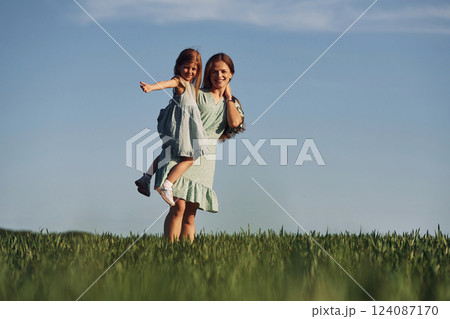 Holding girl on hands. Mother and daughter have fun outdoors on the field at summer Holding girl on hands. Mother and daughter have fun outdoors on the field at summer 124087170