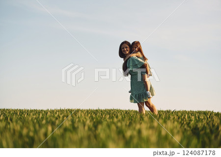 Clear sky. Mother and daughter have fun outdoors on the field at summer 124087178
