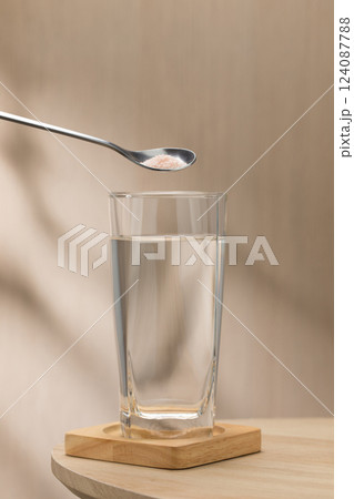 A spoon of Himalayan salt is being added to a glass of drinking water. 124087788