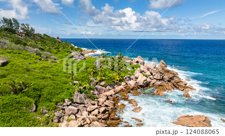 Tropical coast with palm trees, rocky shoreline, and blue waters. La Digue, Seychelles. Tropical coast with palm trees, rocky shoreline, and blue waters. La Digue, Seychelles. 124088065