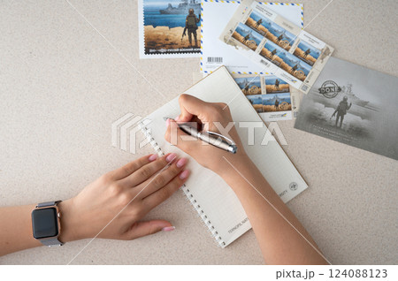TERNOPIL, UKRAINE - June 28: Postage stamps "Russian warship... done". Woman's hands with pen and notepad 124088123
