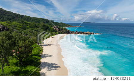 Pristine sandy beach lined with granite rocks and turquoise waters, bordered by lush greenery. La Digue, Seychelles. Grand Anse Beach. Pristine sandy beach lined with granite rocks and turquoise waters, bordered by lush greenery. La Digue, Seychelles. Grand Anse Beach. 124088211