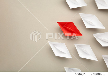 Leadership concept. Red leader paper ship leading among white on grey background. Leadership concept. Red leader paper ship leading among white on grey background. 124088665