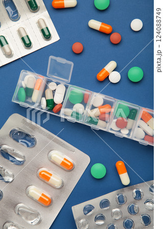 Daily pill box with medications and nutritional supplements on blue background. Space for text 124088749