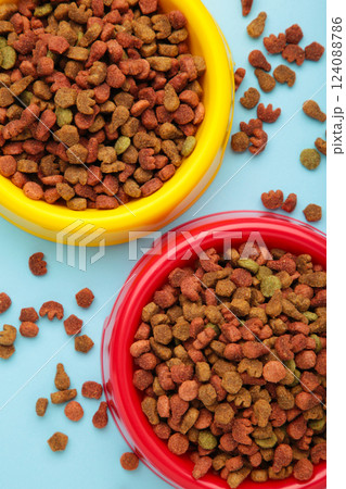 Wet and dry pet food in feeding bowls on blue background. Vertical photo Wet and dry pet food in feeding bowls on blue background. Vertical photo 124088786
