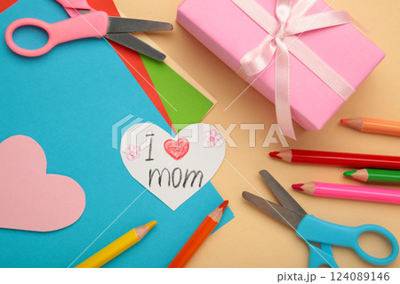 A child draws a postcard for mother's day. Beautiful landscape with mom drawn with pencils. Happy mother's day. Happy birthday card for mom 124089146