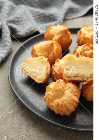 Homemade profiteroles with cream on plate on grey background. Fresh baked golden profiterole. Vertical photo Homemade profiteroles with cream on plate on grey background. Fresh baked golden profiterole. Vertical photo 124089925