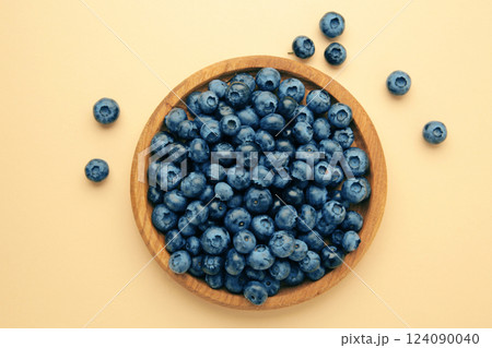 Fresh blueberry in wooden bowl on beige background. Top view. Concept of healthy and dieting eating 124090040