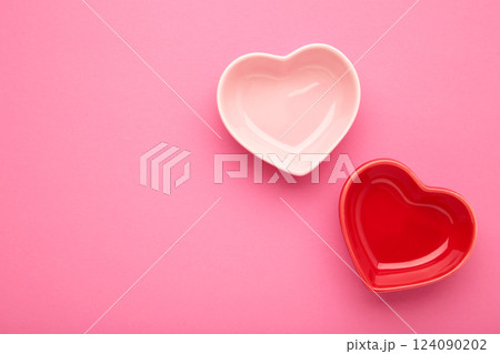 Red and pink heart shaped bowls on pink background. Red and pink heart shaped bowls on pink background. 124090202